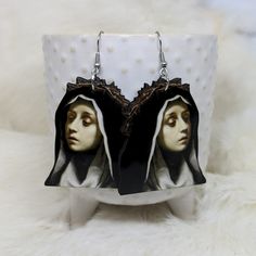 Double Sided Nun Head Earrings  ~ Measures approx. 2- inches ~ Made of lightweight Sublimation  ~ Laser cut and sublimated  ~ Stainless Steel ear wires ~ Hypoallergenic ~ Processing time is up to two weeks as all items are made to order.  May ship sooner if currently in stock. Thanks! follow us @iamsonotcoolvintage on instagram  save 10% :) Artistic Black Drop Earrings, Artistic Black Dangle Earrings, Handmade Halloween Earrings Gift, Artistic Black Nickel-free Earrings, Dangle Earrings As Halloween Gift, Halloween Plug Earrings As Gift, Gothic Hoop Earrings As A Gift, Dangle Earrings For Halloween Gift, Halloween Gift Drop Earrings Jewelry