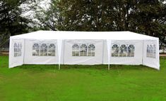 a large white tent with windows in the grass