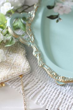 a blue plate sitting on top of a table next to white flowers and a gold chain