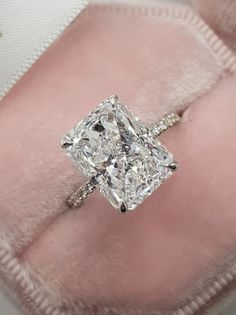 a cushion cut diamond engagement ring on pink velvet