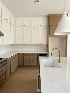 an empty kitchen with white cabinets and wood flooring on the countertops, along with a large island