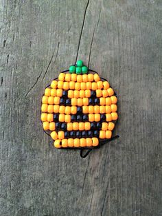 an orange and black beaded pumpkin sitting on top of a wooden table