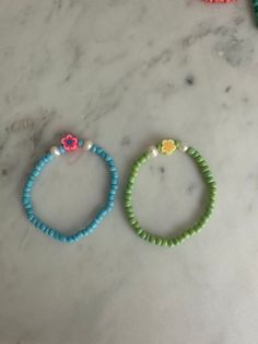 three bracelets with flowers on them sitting on a marble counter top next to each other