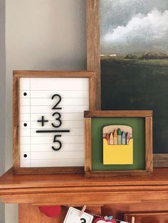 a wooden frame with numbers and pencils in it sitting on top of a mantle