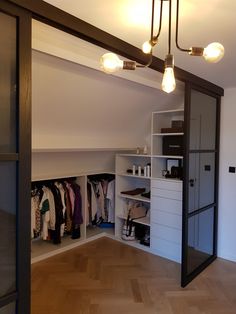 an open closet with lots of clothes hanging on the wall and lights above it,