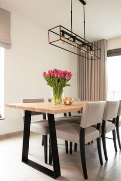 a dining room table with chairs and a vase filled with flowers on top of it