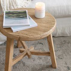 a wooden table with a candle and some books on it next to a white couch