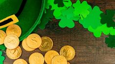 green and gold coins sitting on top of a wooden table next to shamrock leaf decorations