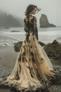 a woman standing on top of a beach next to the ocean wearing a long dress