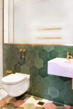 a white toilet sitting in a bathroom next to a sink and tiled floor with hexagonal tiles on it