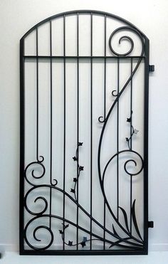 a wrought iron gate with flowers and vines on the bottom, against a white wall