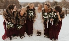 a group of women standing next to each other in the snow with fur stoles