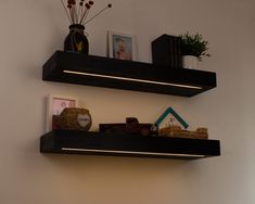 two floating shelves with lights on each shelf above them, along with pictures and other items