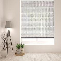 a living room with white walls and wood flooring has a window covered in roman shades