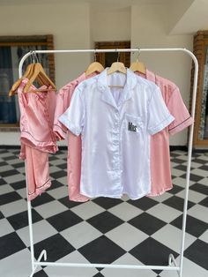 two pink and white shirts are hanging on a rack in front of a black and white checkered floor