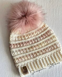 a crocheted hat with a pink pom - pom on top of it