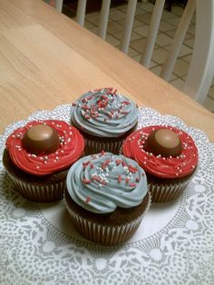 four cupcakes with frosting and sprinkles on a doily