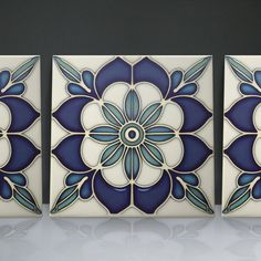 three blue and white tiles with flowers on them