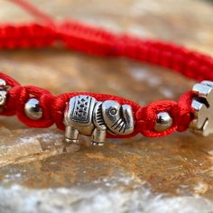 Bracelet w/4 traditional good-luck charms. Adjustable one size fits most, from 3" to 9". St Benedict, Hamsa Hand, Elephant, Four-Leaf Clover. Ends of the drawstrings have a round bead. Red with silver-tone over base metal charms. Get luck on your side with this charming bracelet. FREE SHIPPING in the USA. Order now! Charming Bracelet, Good Luck Bracelet, Red Bracelet, St Benedict, Saint Benedict, Metal Charms, Red Bracelets, Four Leaves, Luck Charms