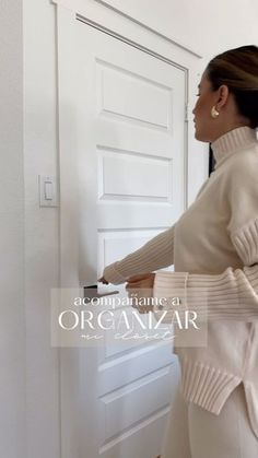 a woman is opening the door with her hand and looking at something on the wall