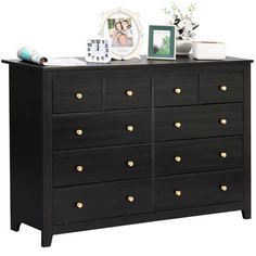 a black dresser with many drawers and pictures on top of it, along with other items