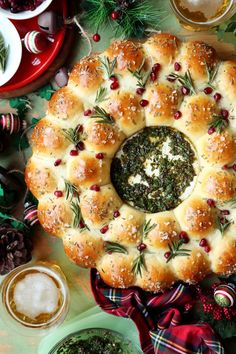 an overhead view of a christmas wreath - shaped bread dish surrounded by other holiday foods