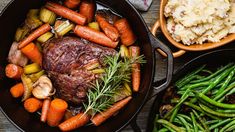 an assortment of vegetables and meat in pans on a table with mashed potatoes