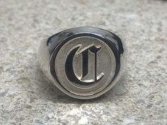 a ring with the letter u on it sitting on top of a marble countertop