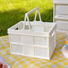 a white basket sitting on top of a table next to a cake