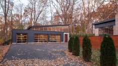 two garages in the middle of a wooded area with lots of leaves on the ground