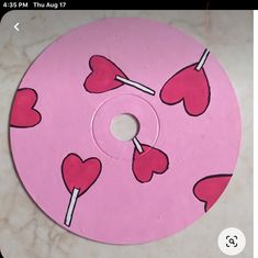 a pink disc with hearts and lollipops on it sitting on a table