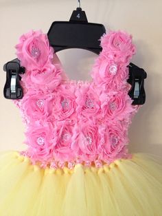 a pink and yellow dress with flowers on the front, attached to a hanger