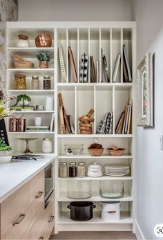 a kitchen with white shelving filled with lots of dishes and cooking utensils