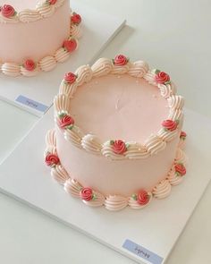 two cakes with pink frosting and roses on them