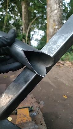 a close up of a person holding a metal object in their hand with trees in the background