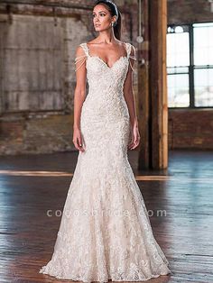 a woman in a wedding dress standing on a wooden floor with an industrial building behind her