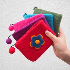 a hand is holding three small pouches with pom - poms on them