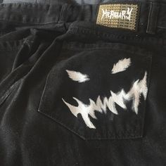 a pair of black jeans with white teeth painted on the front and back pockets