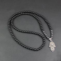 Inspired by Middle Eastern symbolism, the striking beauty of this Natural Onyx Beaded Long Necklace has a unique versatility and can easily be worn by either men or women. With a longer length design, this decorative piece features naturally toned Onyx beads - each unique in their design and boasting a gentle array of colour. Breaking up the darkened silhouette are three intricate skull beads and glass charms that capture the light and emit a colourful array. The necklace has been finished off w Black Polished Beads Necklace For Meditation, Black Spiritual Beaded Necklaces, Spiritual Black Beaded Necklaces, Black Polished Beads Necklace For Healing, Black Spiritual Beaded Necklaces With Polished Beads, Black Hand-strung Bohemian Necklace, Black Wooden Beads For Meditation, Black Bohemian Hand-strung Necklaces, Onyx Bead Necklaces For Meditation