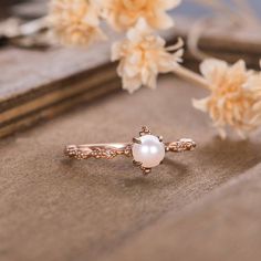 a pearl ring sitting on top of a book next to flowers