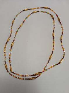 a long beaded necklace with gold and multicolored beads on a white surface