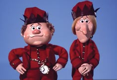 two cartoon characters dressed in red suits and hats, one holding a pocket watch while the other is wearing a clock