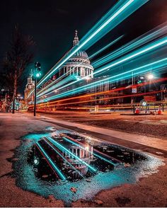 a city street at night with lights streaking over the road and buildings in the background