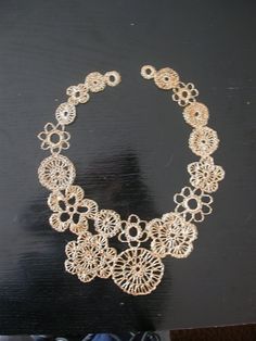 a gold necklace is displayed on a black surface