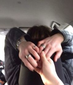 two people holding each other in the back seat of a car with their hands together