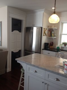 a kitchen with white cabinets and marble counter tops, along with a stainless steel refrigerator