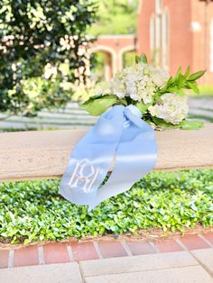 a blue ribbon tied to a bench with flowers on it