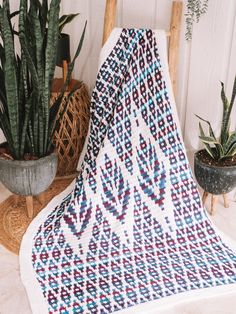 a crocheted blanket sitting on top of a table next to potted plants