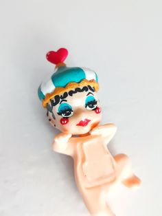 a toy figurine that is laying down on the ground with a heart on it's head