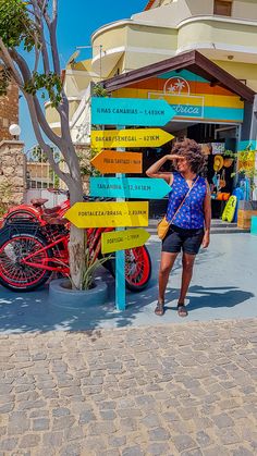 a woman standing next to a colorful sign in front of a building